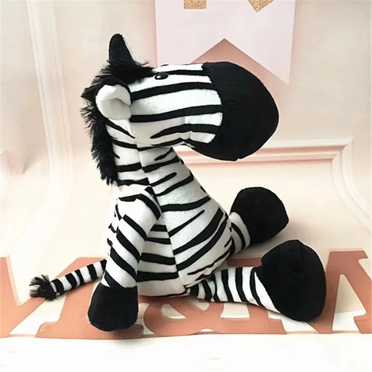 Uma zebra de pelúcia fofa branca com listras presta, está sentado em um mesa branca, com detalhes em rosa.